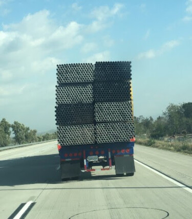 A truck with many metal pipes on a trailer